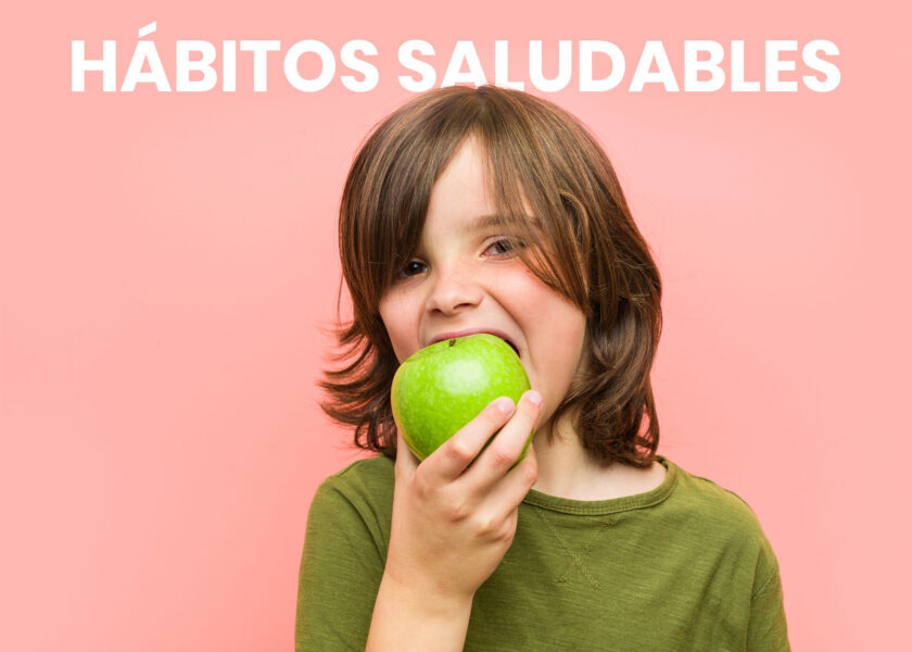 niño mordiendo una manzana verde con fondo rosado